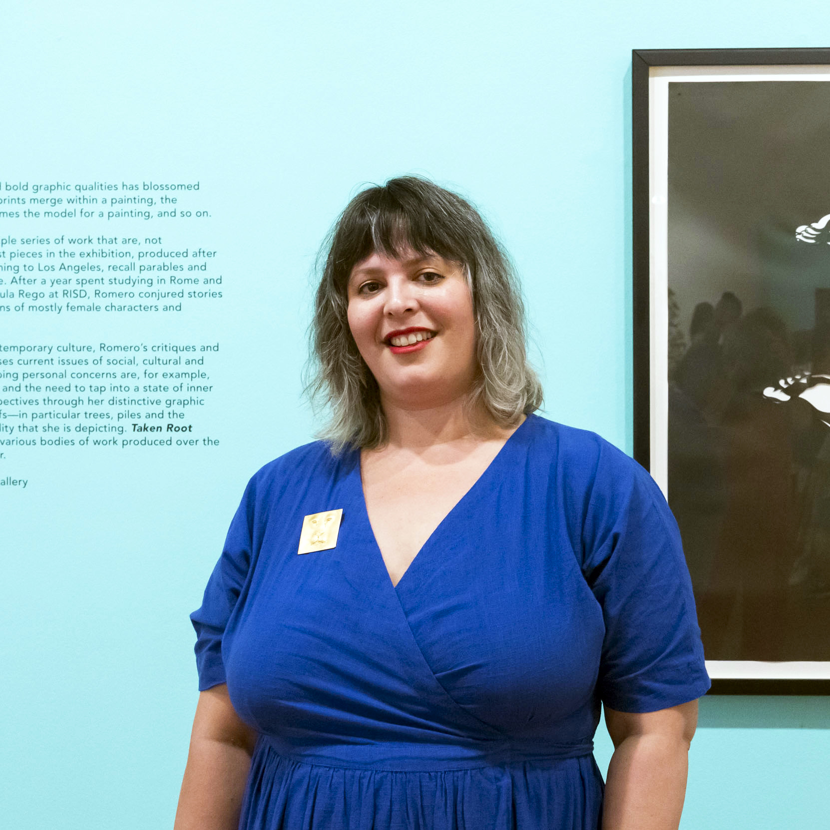 An artist stands in a gallery with a blue wall